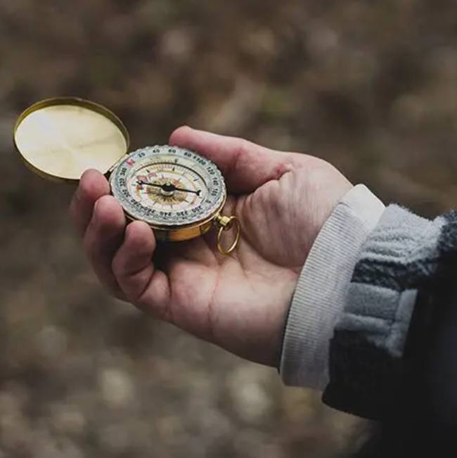 A person holding a compass in their hand.